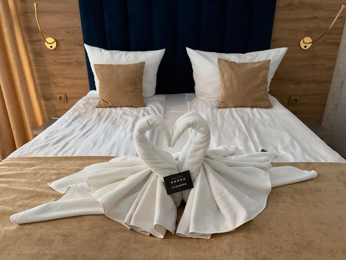 Schlafzimmer mit frisch bezogenem Bett und gerollten Handtüchern